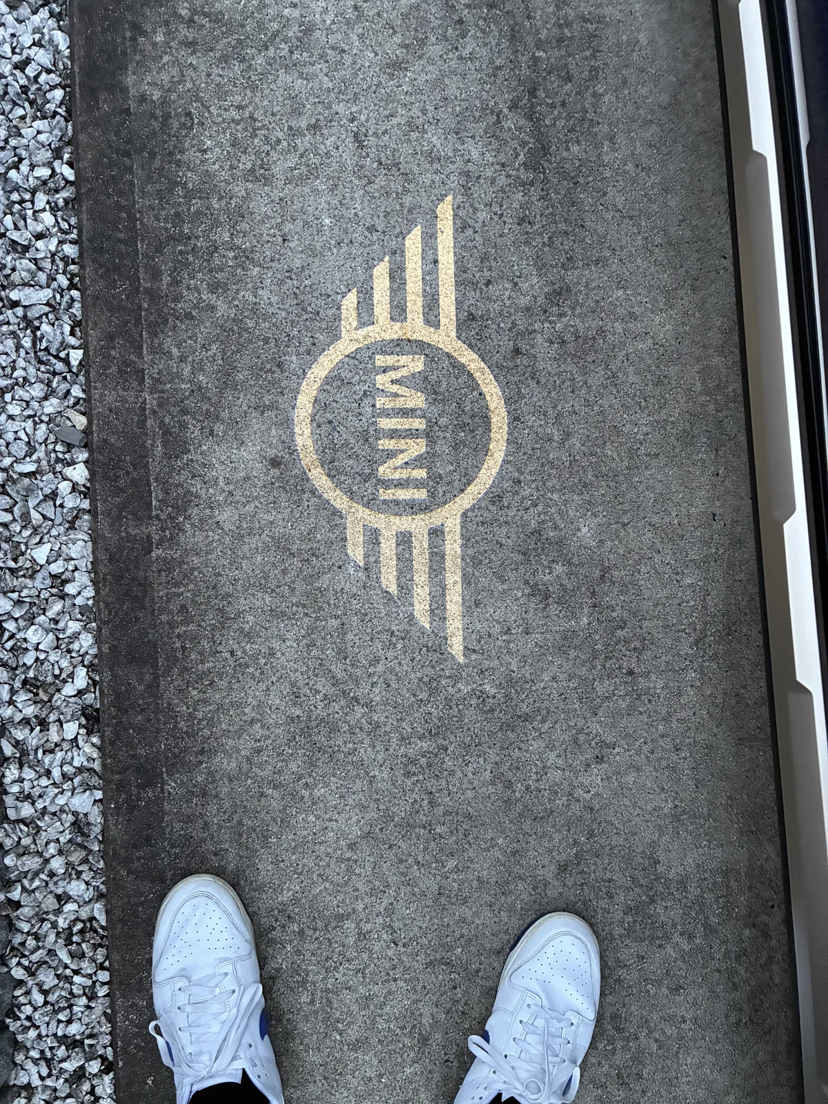 車の横の路面に投影されたMINIのロゴと、足元の白いスニーカー