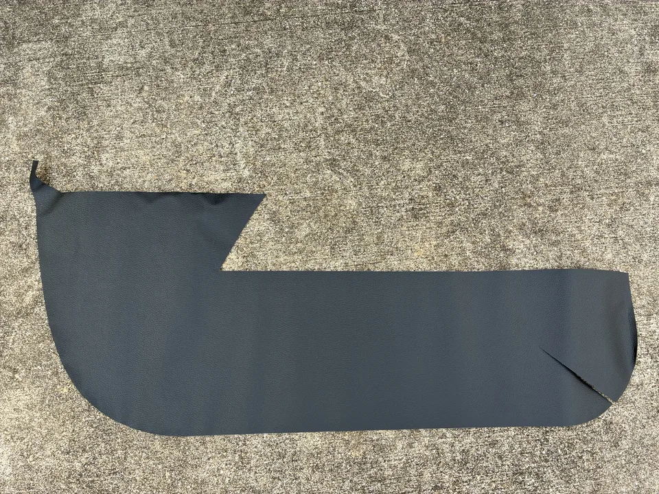 車内のマット上に単体で広げた黒いキックガード。上側と下側に切り込みのある形が見える。